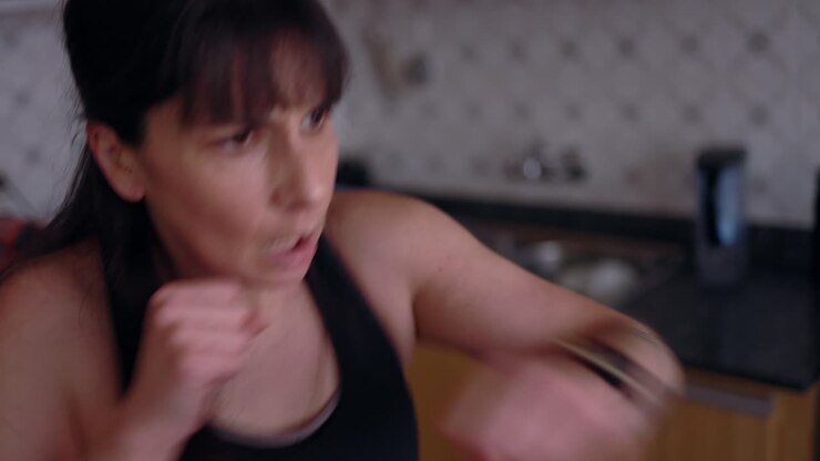Woman taking online fitness boxing lessons at home, in the kitchen