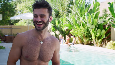 retrato de un hombre hispano sonriente de pecho desnudo al aire libre con amigos disfrutando de una fiesta en la piscina de verano