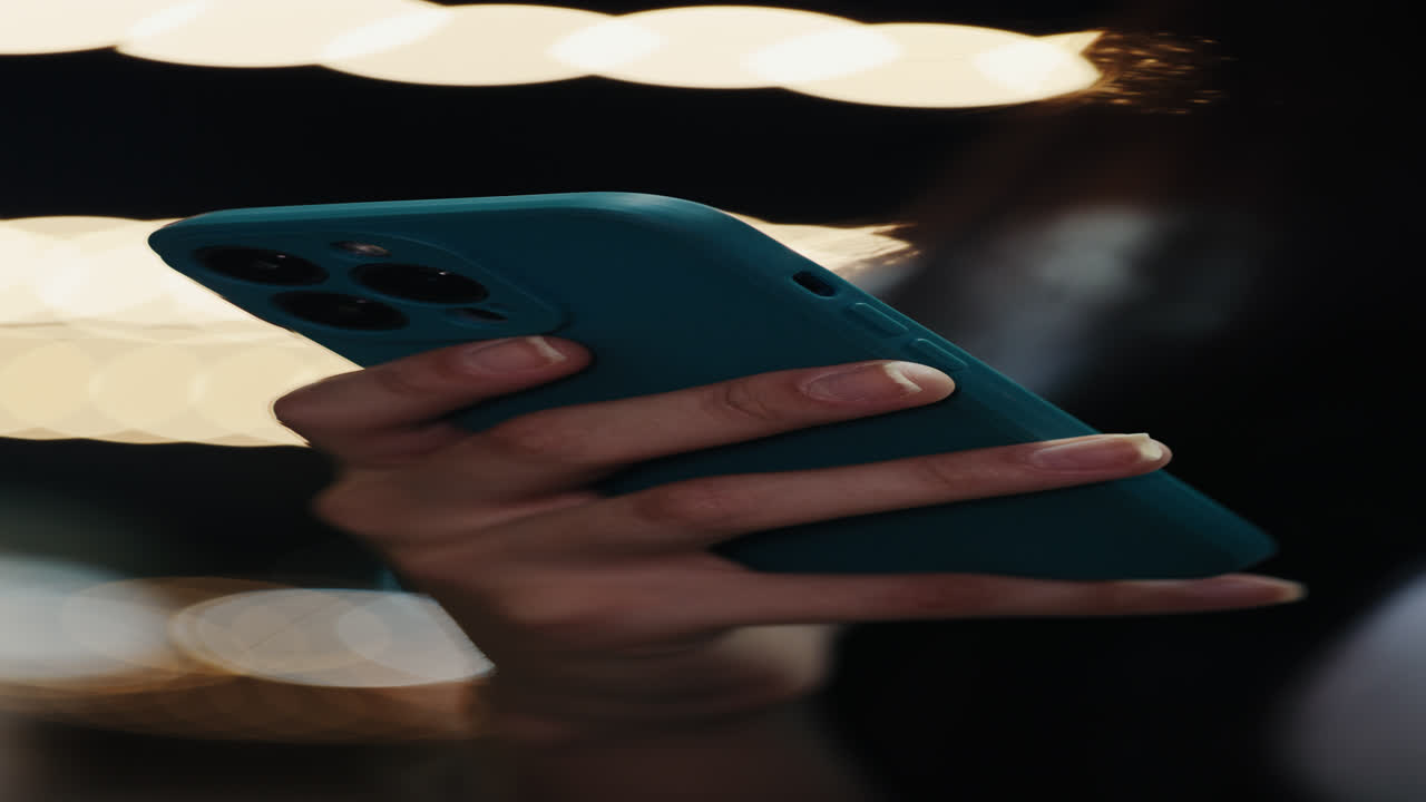 Woman using teal smartphone at night