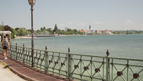 woman walking overlooking lake constance bodensee with view of friedrichshafen, germany