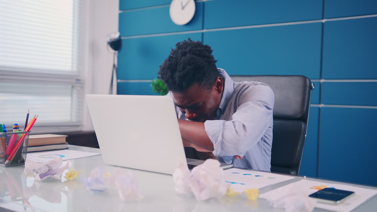 Overworked african american man checking time falling asleep at work desk
