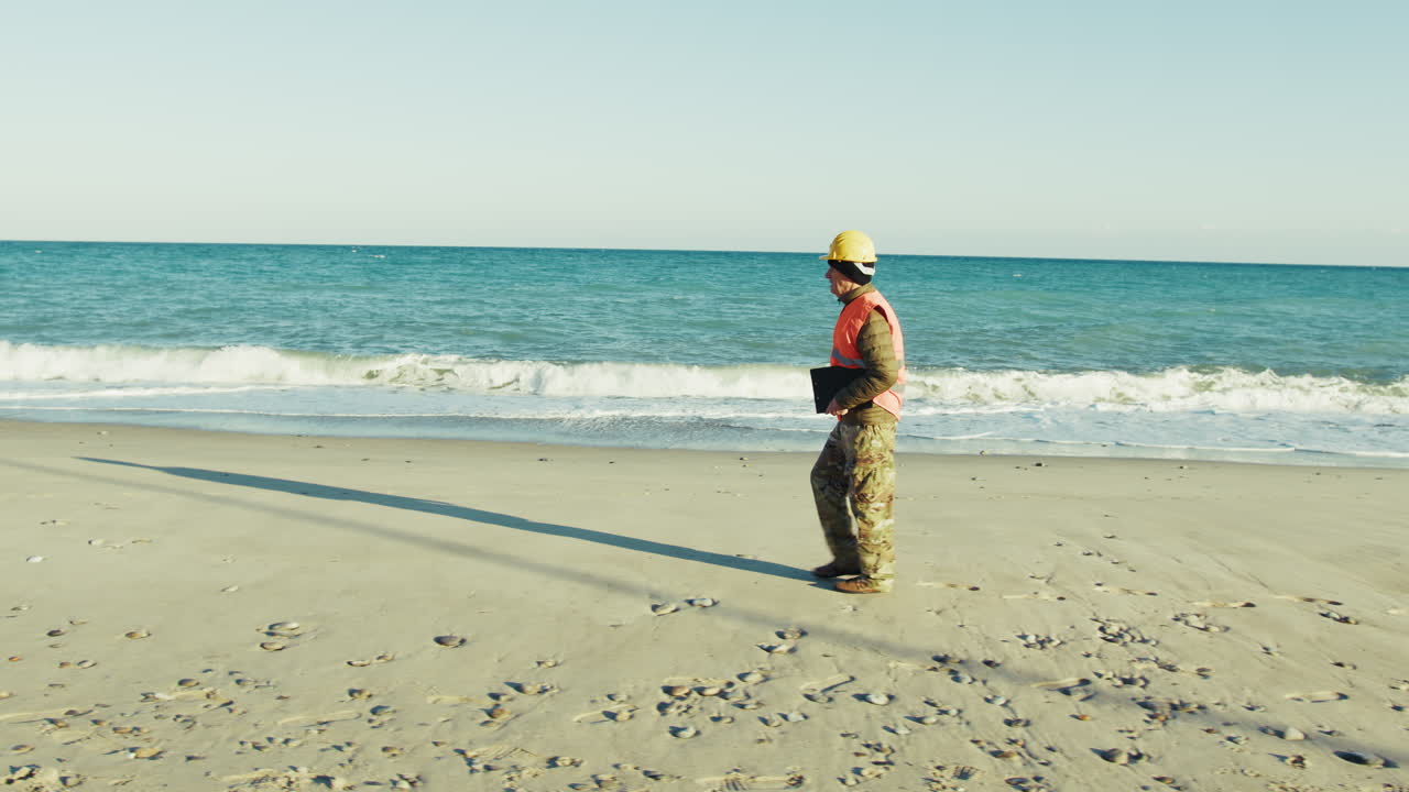 Experienced Engineer Walking Along the Beach Under the Sun