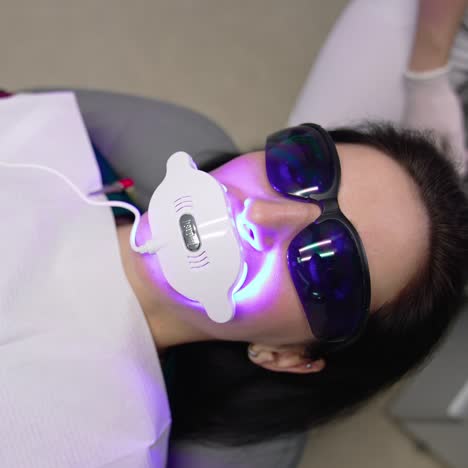 dentist treating teeth of female patient. female dentist whitening young girl patient teeth at dental clinic