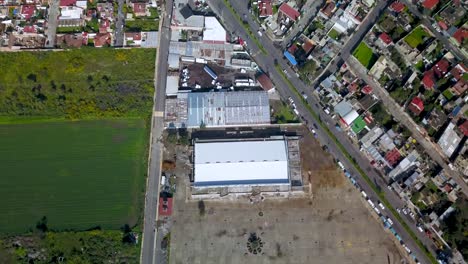 Top-drone-view-of-a-warehouse-and-market-in-the-charming-town-of-chalco-Mexico,-and-view-of-the-highway-town-and-houses-population-density