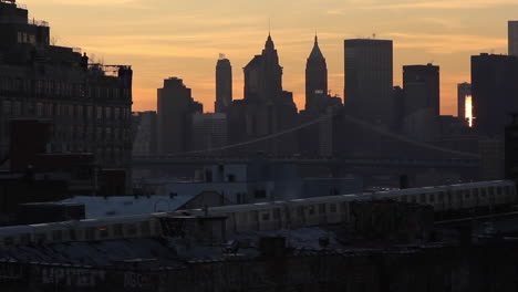 sunrise subway train moves into the city across the bridge, from brooklyn to manhattan skyline