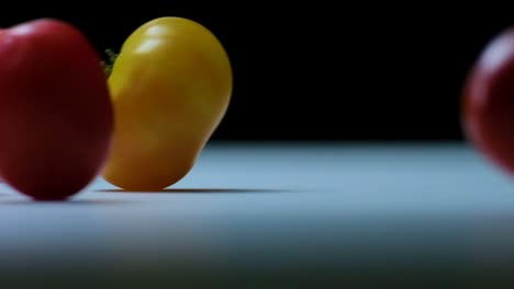 movimiento lento de tomates delicados cayendo en una mesa blanca