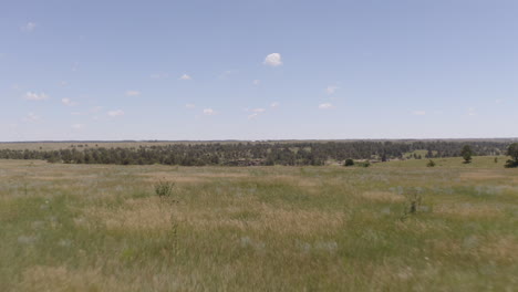 aerial views of a grassy plane heading to a beautiful rock formation in palmer lake colorado