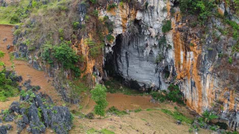 exterior wall and entrance to limestone cave somewhere in vietnam, aerial, parallax