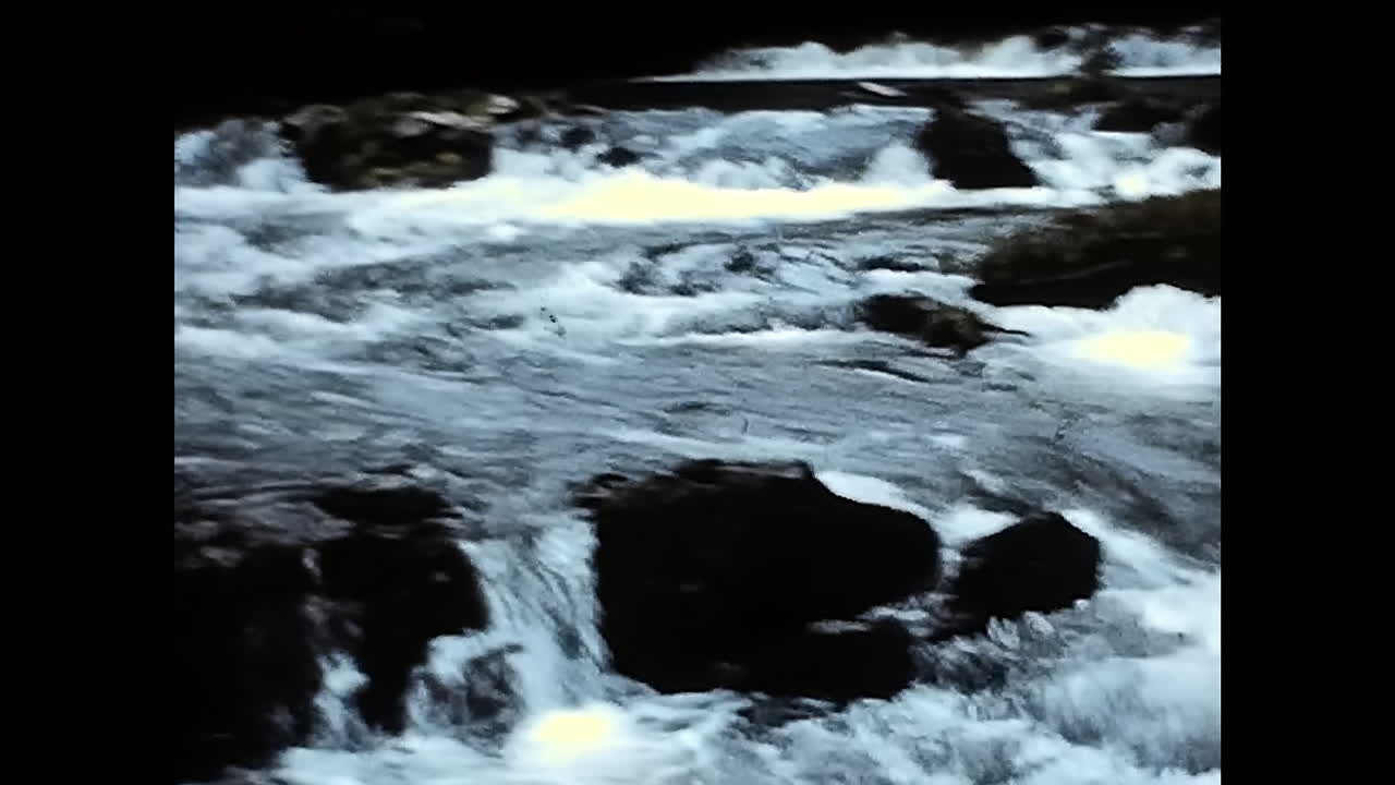 Rushing Water Over River Rocks in 1970s USA. CIRCA USA - 1970s: Spectacular footage of water forcefully cascading over rocks in a river during the 1970s in the United States.