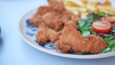 crispy fried chicken tenders with french fries and salad