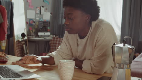 Mujer-Negra-Tomando-Café-Y-Usando-Una-Laptop-En-Casa