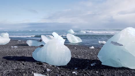 Eisbrocken-Am-Diamond-Beach-In-Island-Schmelzen-In-Der-Sonne,-Meereswellen