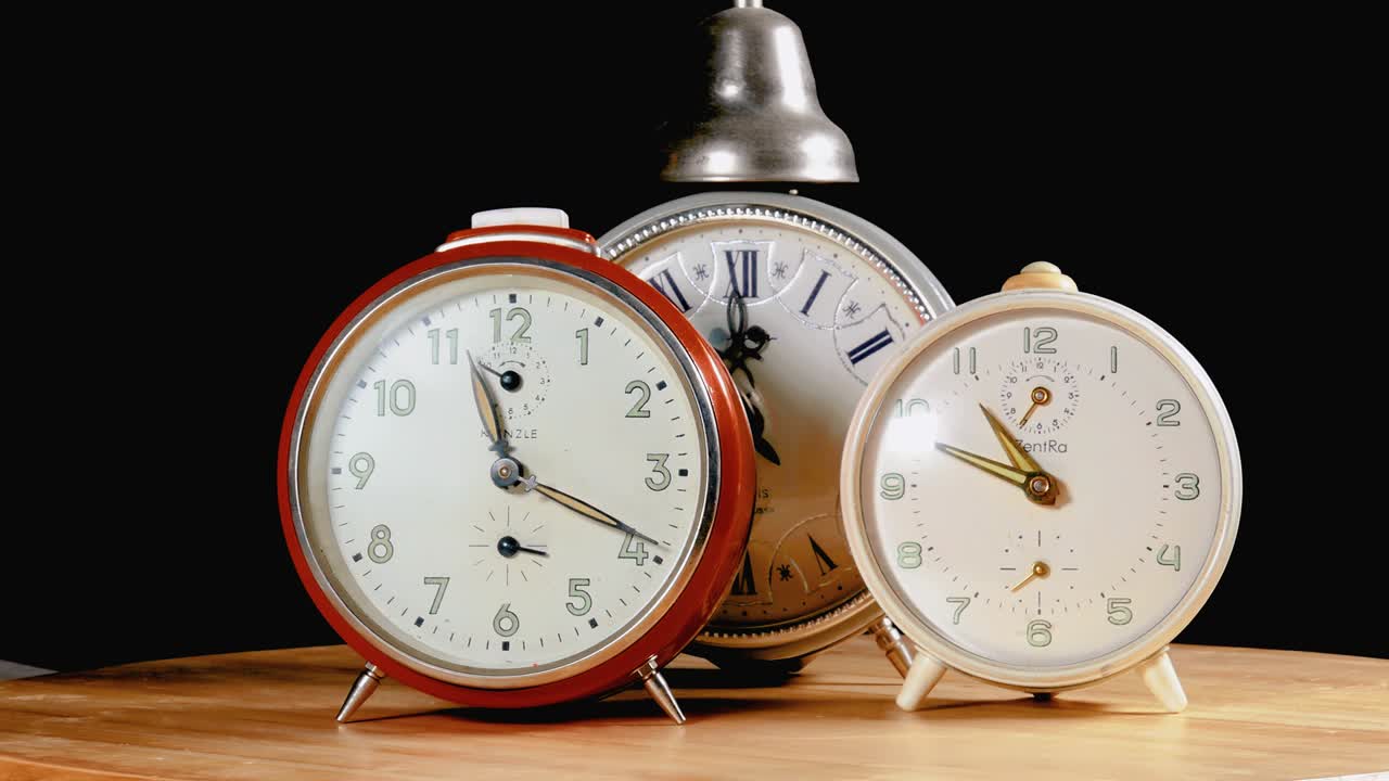 tres relojes despertador de escritorio retro vintage como órbita girar en la mesa de madera con fondo negro