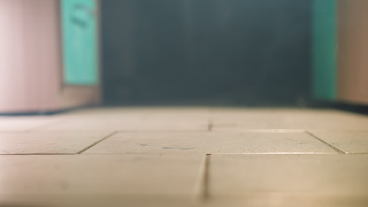 타일로 된 바닥에 떨어지는 스마트폰의 클로즈업 뷰, 바닥에 부힌 후 공중에 회전하는 모습