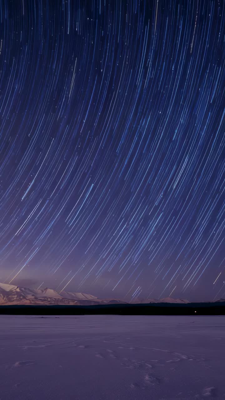 Vertical video: Timer starting star trails sweeping over frozen lake to show sky motion, ridge