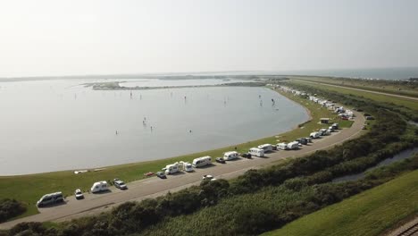 Fila-De-Campistas-Estacionados-Y-Gente-Haciendo-Windsurf-En-Brouwersdam-En-Los-Países-Bajos-Durante-Un-Día-De-Verano