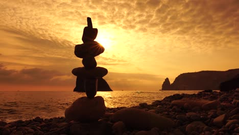 pyramid stones on the seashore with warm sunset on the sea background. happy holidays. pebble beach, calm sea, travel destination. concept of happy vacation on the sea, meditation, spa, calmness