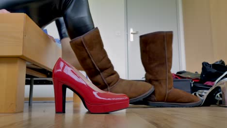 a woman in shiny black leggings takes off her lambskin boots and puts on her red high-heeled stilettos