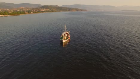 Aerial:-A-fishing-boat-in-the-bay-in-front-of-Molyvos,-Greece