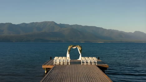 wedding ceremony setup on a pier over a lake with mountains