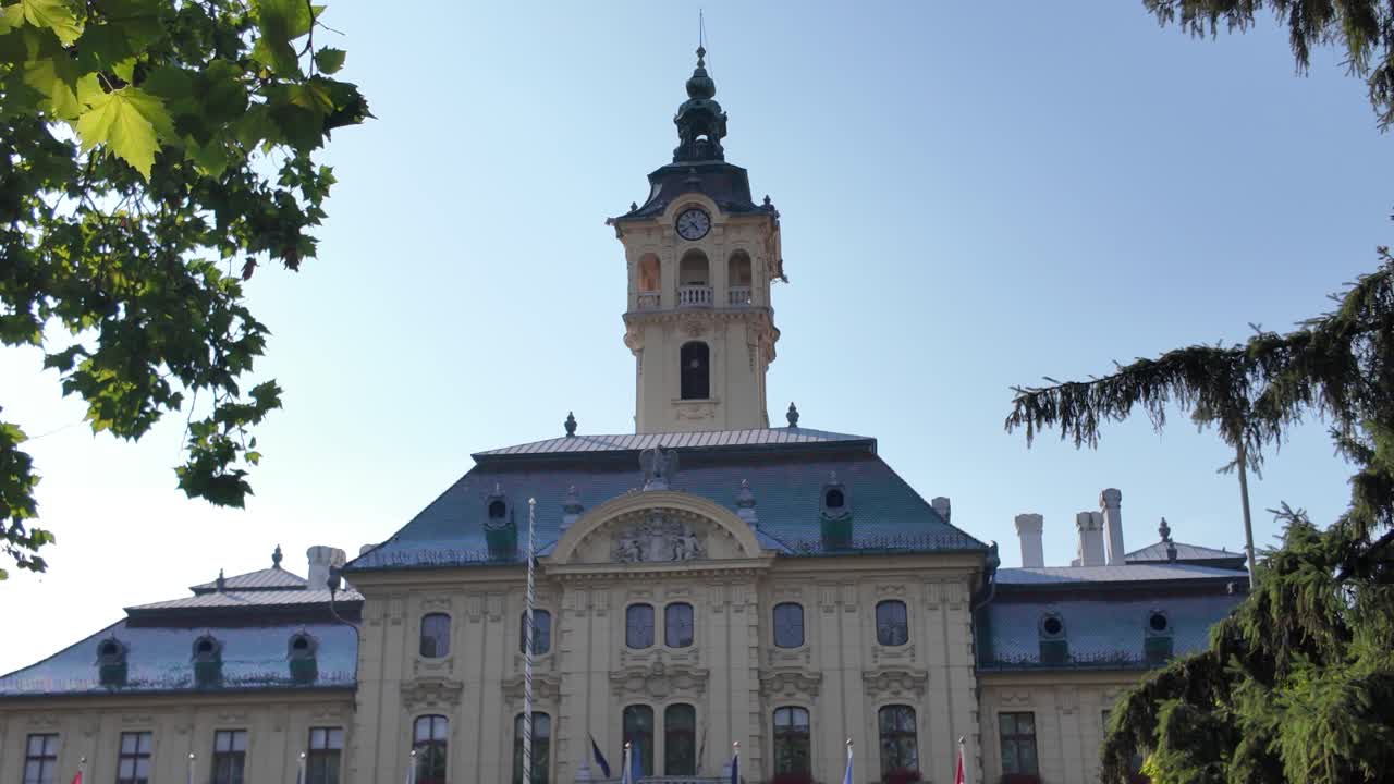 Pan shot moving from a fountain in front of Szeged City Hall to the historic town hall tower, highlighting architectural details