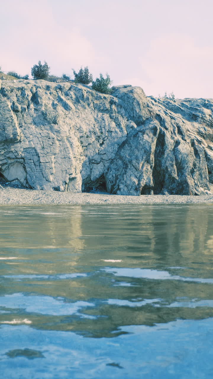 Serene shoreline with calm water reflecting rocky cliffs and greenery