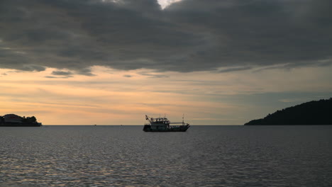 Trawler-Fischerboot-Vertäut-In-Einem-Meer-Vor-Brennendem,-Lebendigem-Sonnenuntergangshimmel-In-Der-Nähe-Von-Silhouetteninseln-Im-Hafen-Von-Kota-Kinabalu,-Malaysia