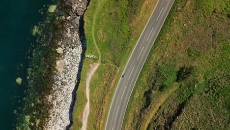 overhead aerial video of a road on the causeway coastal route in county antrim, northern ireland, uk, on a bright and sunny day. filmed in 4k, 60fps and with rec709 color.