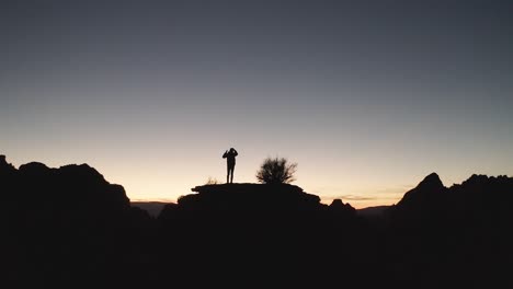 Silueta-De-Un-Hombre-En-Una-Colina,-Contemplando-La-Vida-Mientras-Mira-Desde-Una-Vasta-Puesta-De-Sol-En-El-Desierto