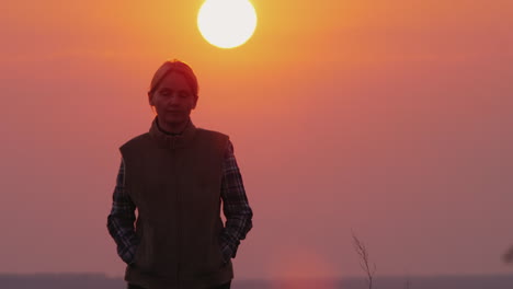 A-Woman-Walks-Toward-The-Camera-A-Large-Red-Sun-Shines-From-Behind