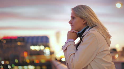 a young woman stands leaning on the railing of the bridge admiring the beautiful sunset 4k video