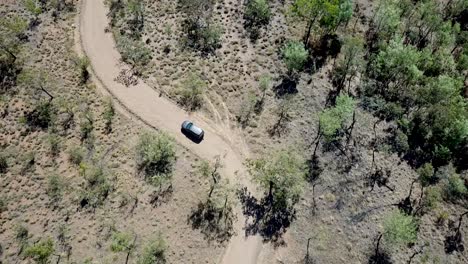 toma de arriba hacia abajo de un todoterreno conduciendo por el campo seco de australia en un camino de tierra