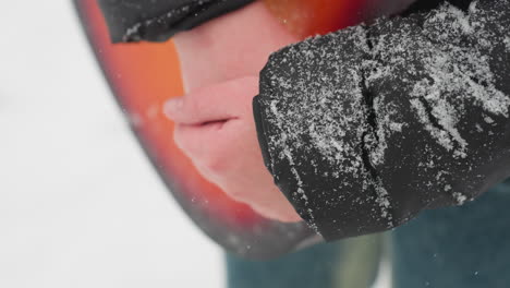 close-up of hands holding a vibrant red acoustic guitar in a snowy winter scene, with snowflakes delicately resting on black jacket sleeve