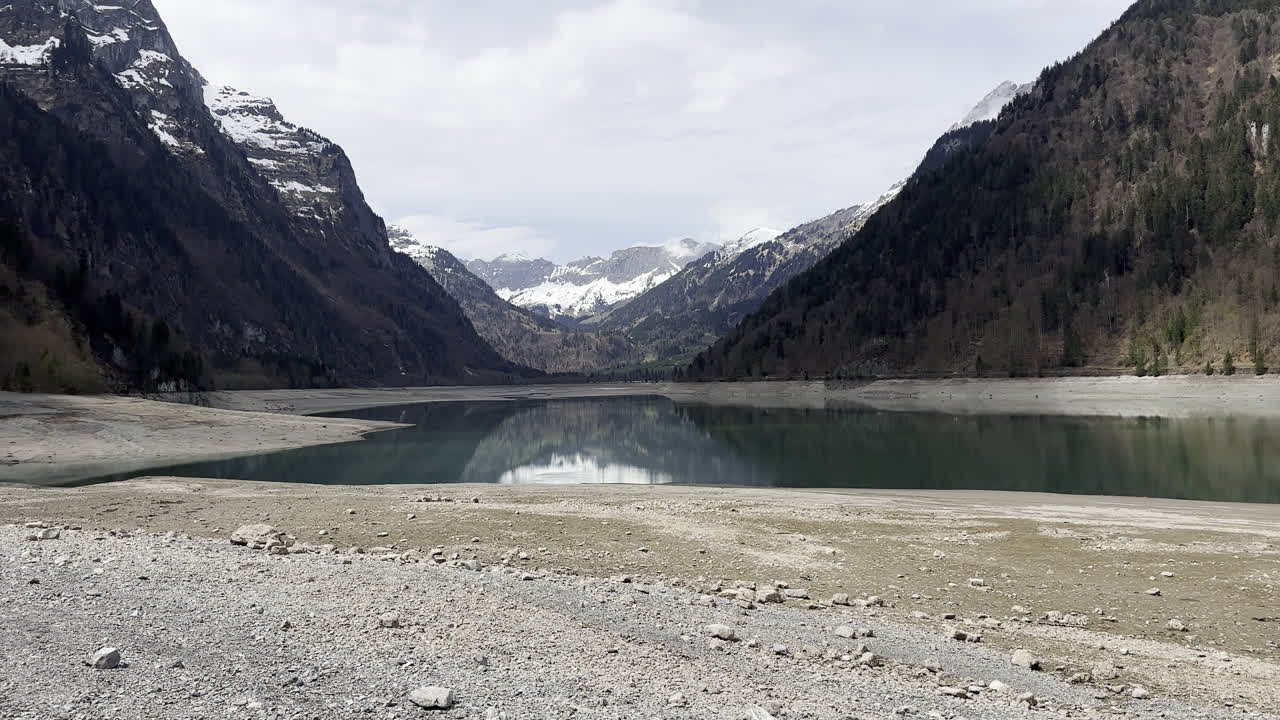 Static view of suggestive alpine lake inside mountains with an happy dog playing