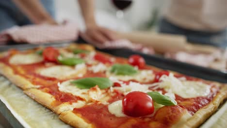 tracking video of sprinkling homemade pizza with cheese.