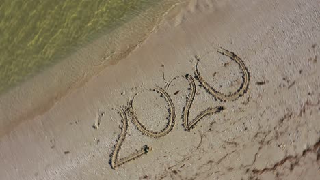 twenty twenty written in the sand and spinning clockwise showing it as a crazy year