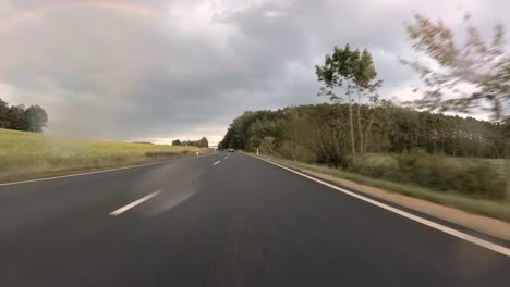first person view of driving over a german highway on a rainy day seeing a rainbow in front, 4k