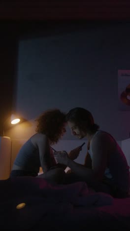 couple using phones in bed at night