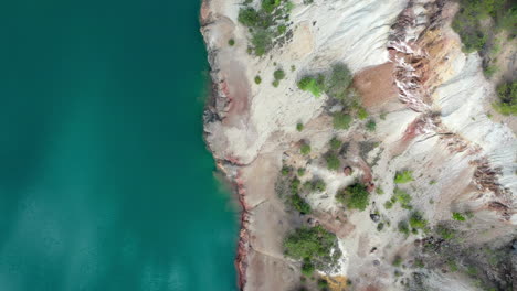 Volar-De-Arriba-Hacia-Abajo-Sobre-La-Vista-De-Un-Sitio-De-Construcción-De-Una-Mina-Con-Un-Lago-Azul