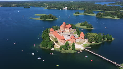 aerial: rotating shot of trakai castle with boats and yachts circling on lake around the trakai castle island