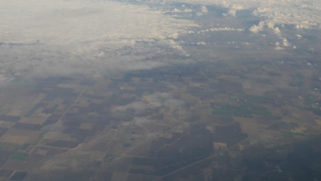 aerial view of clouds and greenery out from flying airplane window shot in 4k high resolution