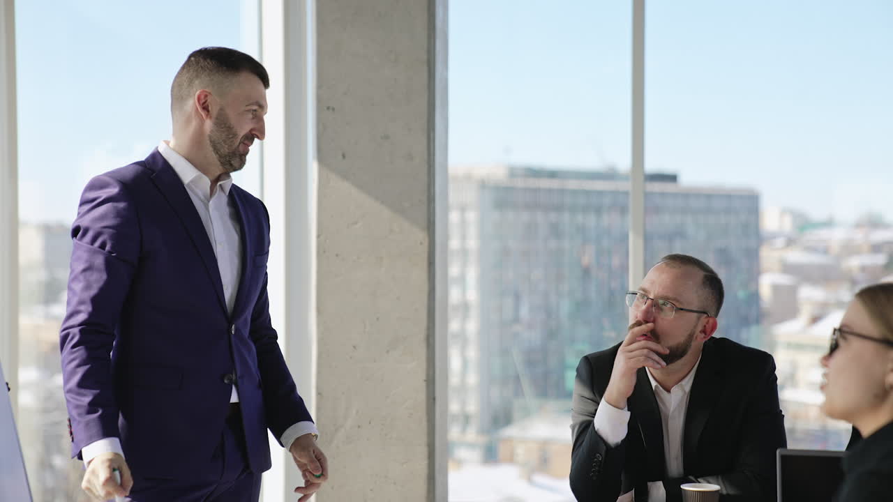 Company employers discussing the business issues. Two colleagues brainstorming looking at the chart. Business people in the light office.