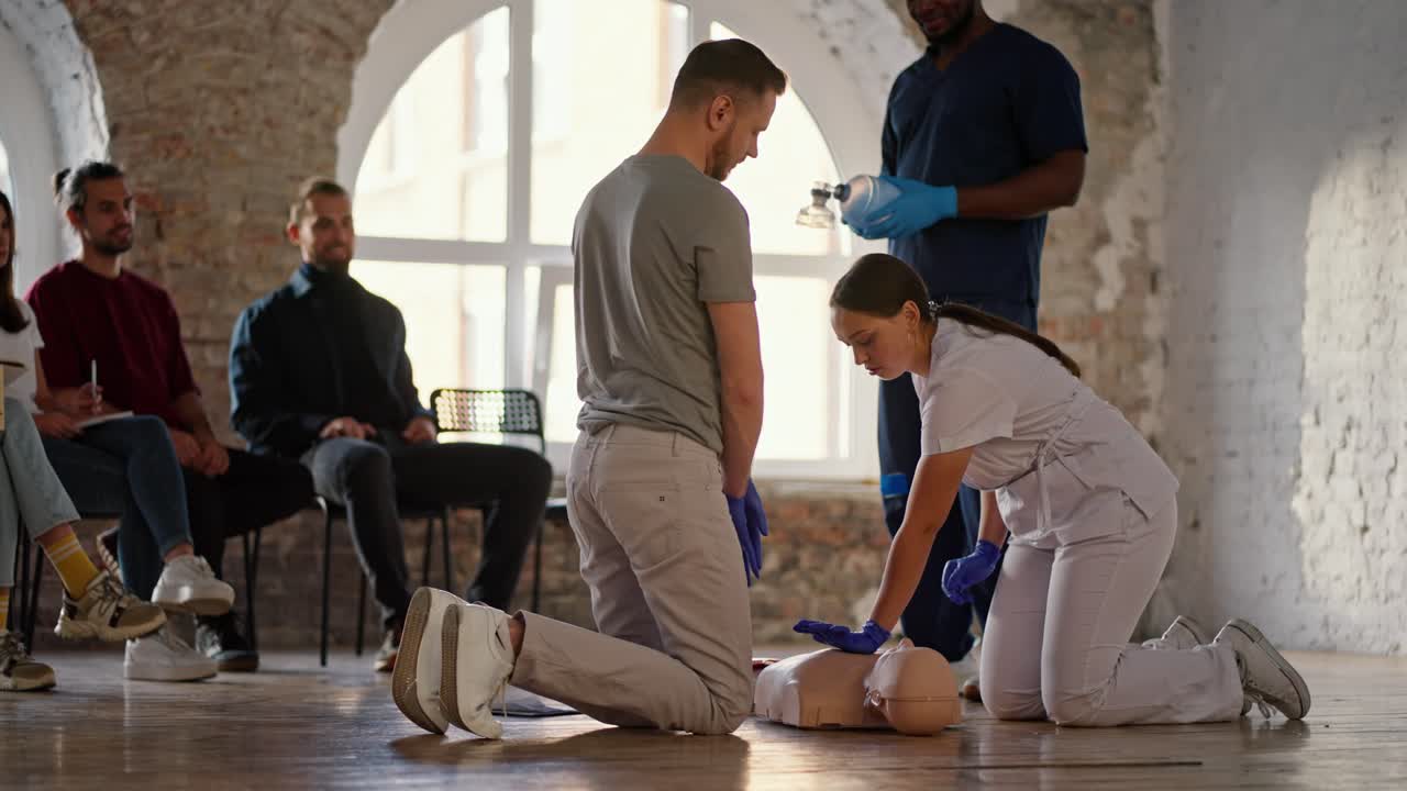 enfermera profesional en uniforme médico blanco enseña a una morena barbuda a hacer un maniquí de respiración artificial en un curso práctico para un médico