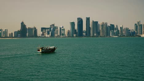 traditional fishing boat passing near skyscrapers in doha qatar middle east