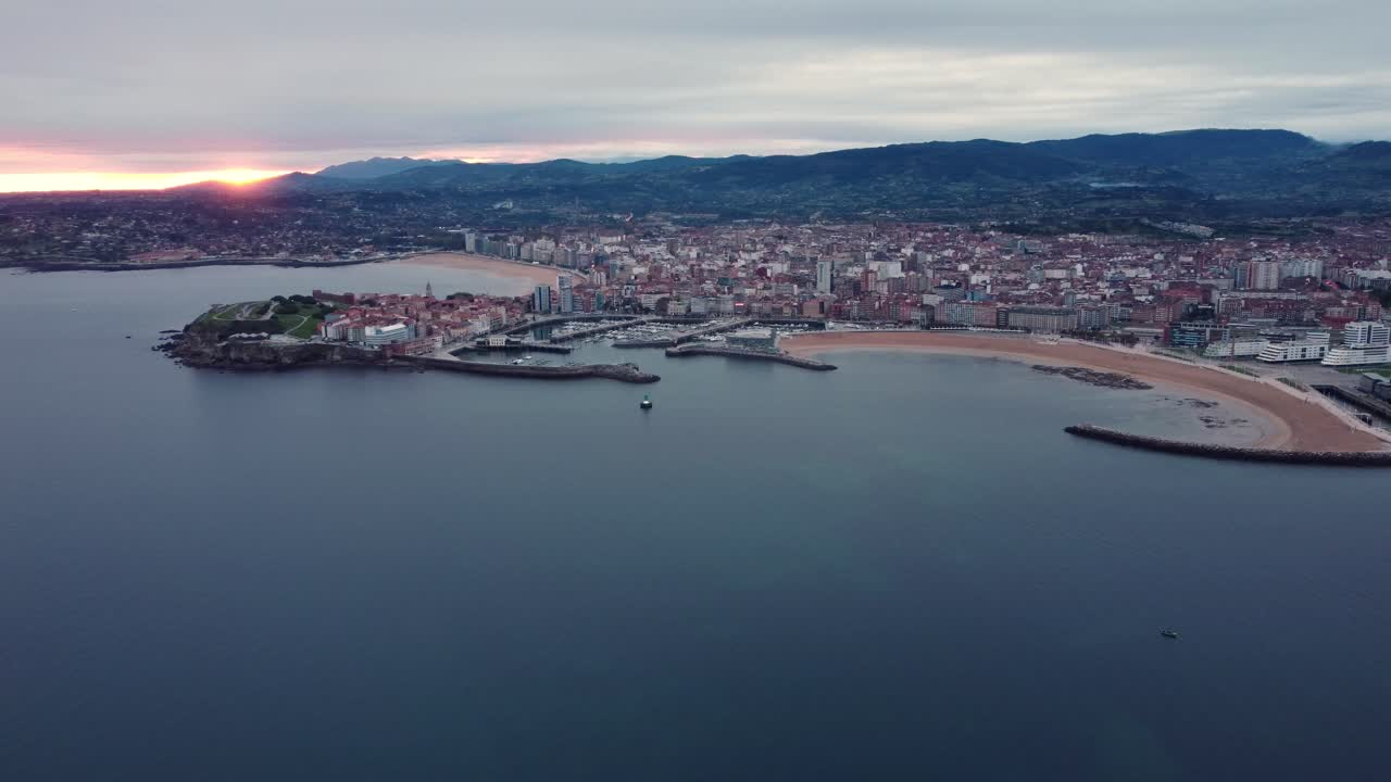Drone che sorvola la città di Gijón, nel nord della Spagna, regione delle Asturie, paesaggio urbano al tramonto con vista sull'oceano.