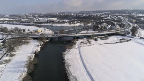 Aerial-View-of-Bridge-Overpass-Ruhr-River-on-Sunny-Winter-Day,-Snowcapped-Fields-and-Hattingen-City-in-Background,-Germany
