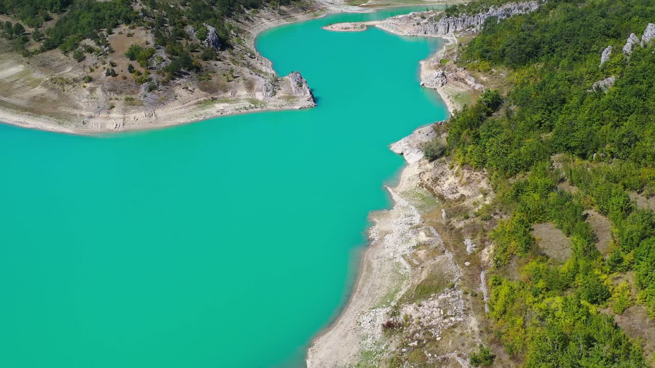 Zeleno jezero water reservoir lake in Croatia with slim water channel in opaque blue, Aerial dolly out shot