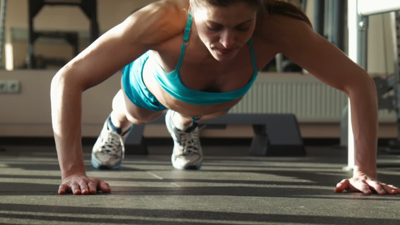 The Woman In Sportswear Does Push-ups In a Gym