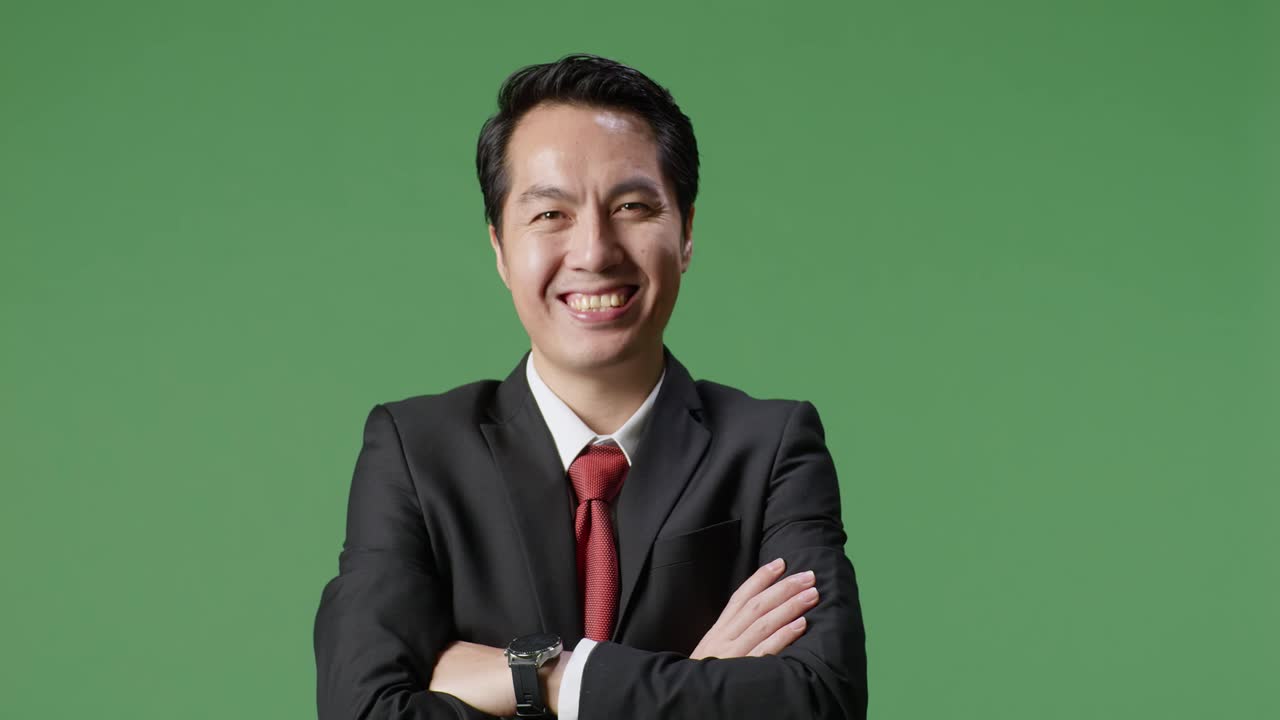아시아 사업가 한 명 은 스튜디오 의 초록색 스크린 배경 에 팔 을 고 따뜻 한 미소 를 지었다
