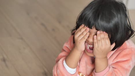 happy little girl hiding her face